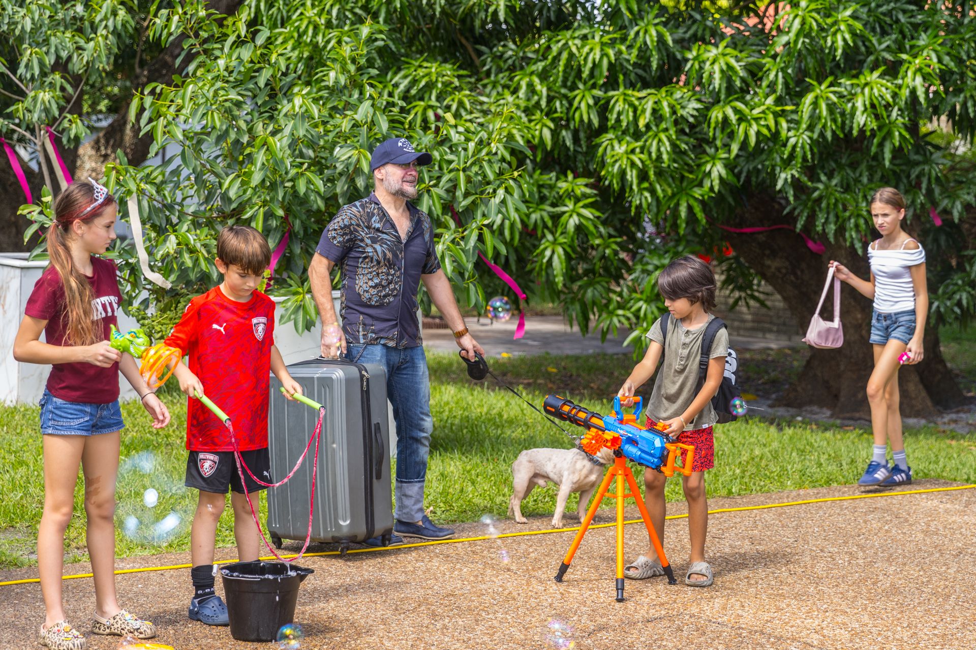 Children chase giant soap bubbles across the lawn