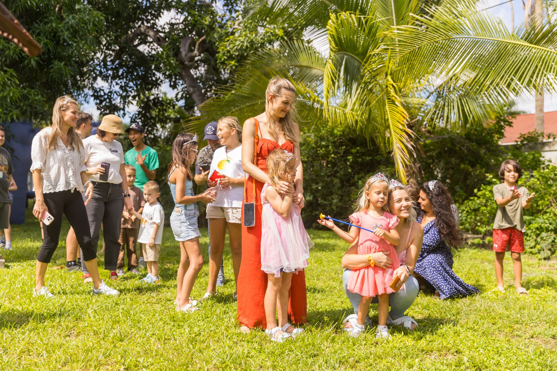 Children with toy wands and tiaras stand ready on the lawn